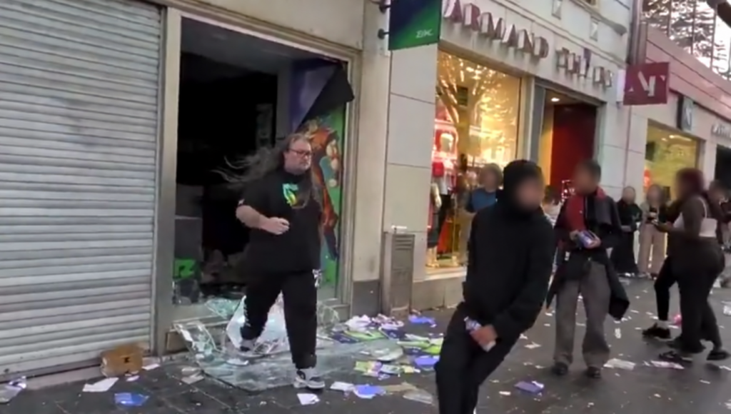 Un vendeur devant la vitrine brisée d'un magasin de jeux vidéo, avenue Jean-Médecin à Nice, au milieu de débris, lors des violences du 17 octobre