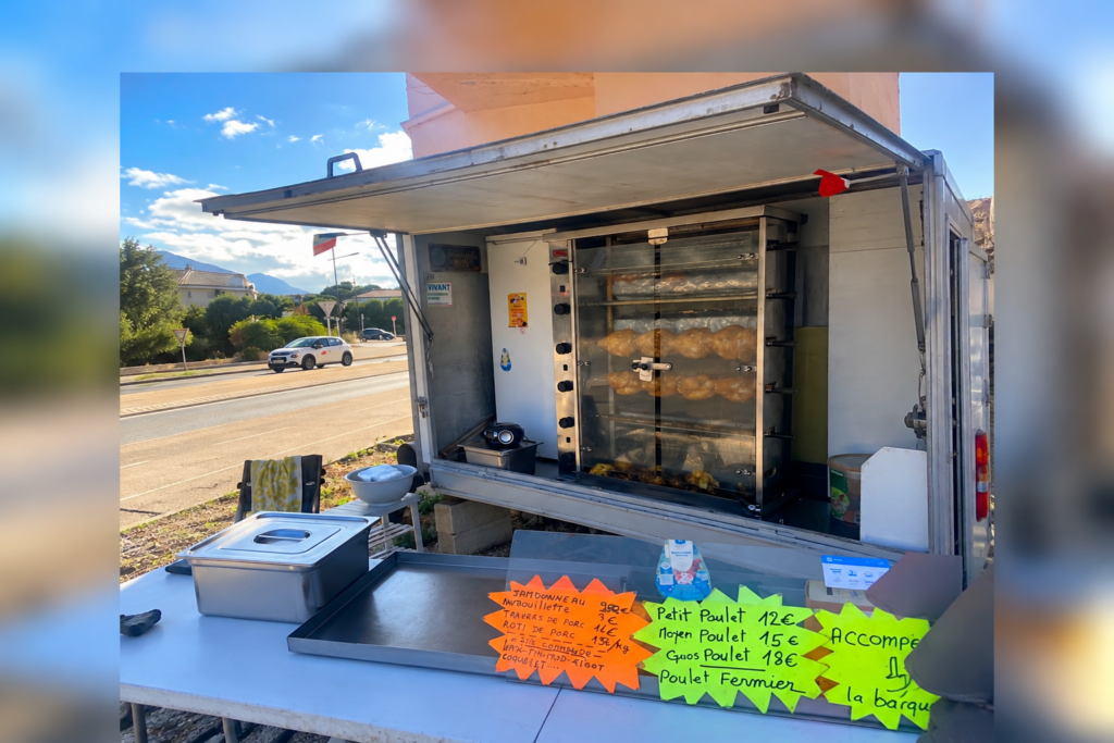 Camion de rôtisserie avec poulets rôtis et pancartes de prix, installé en bord de route