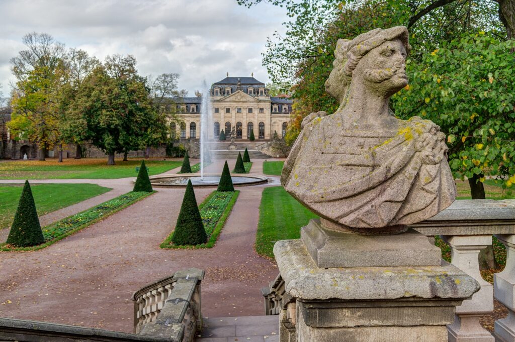 Jardin en automne avec pelouse, arbres à feuilles jaunes et allées bordées de plates-bandes
