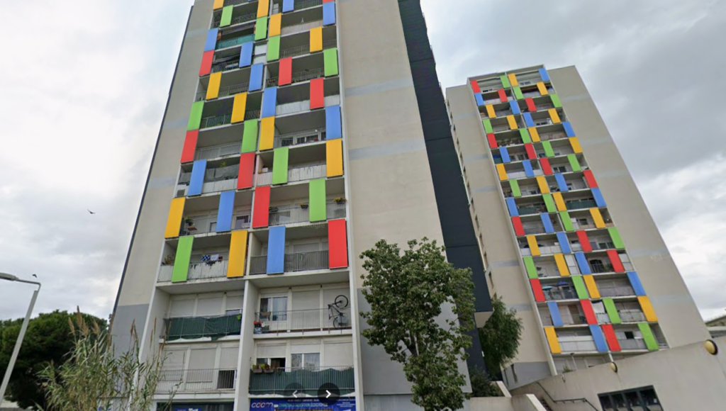 Deux tours d'immeubles de logements sociaux aux balcons ornés de panneaux colorés rouges, bleus, jaunes et verts