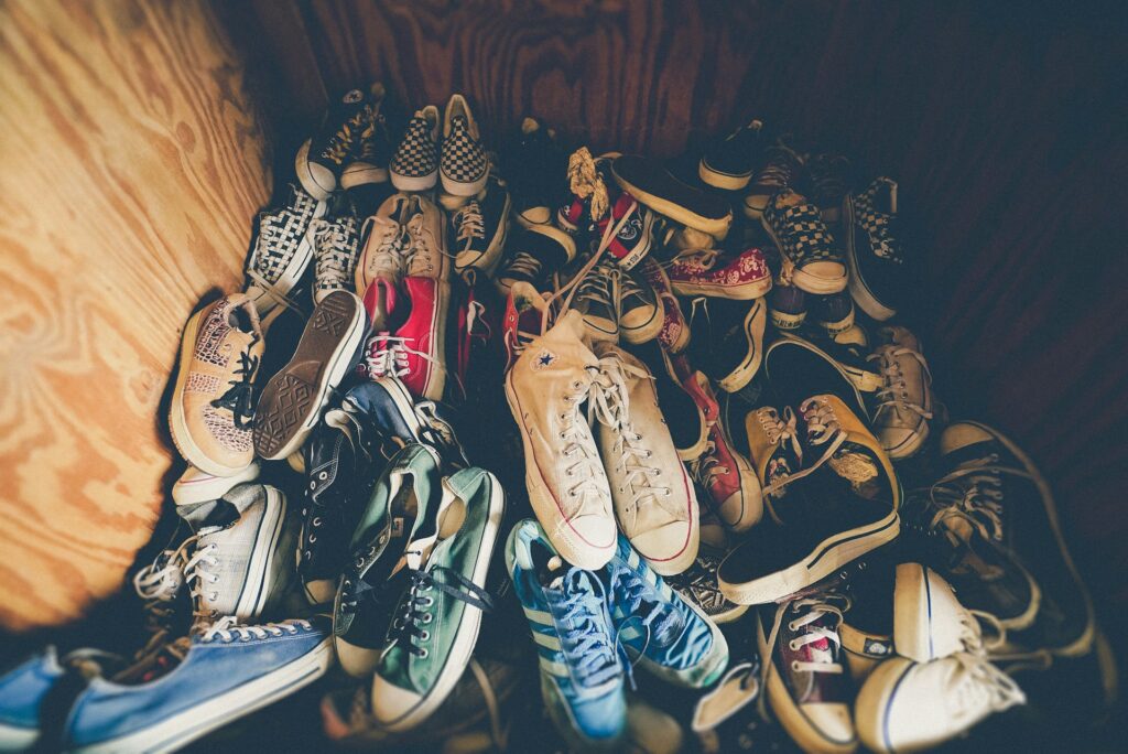 Tas de baskets de différentes couleurs et marques empilées sur un sol en bois