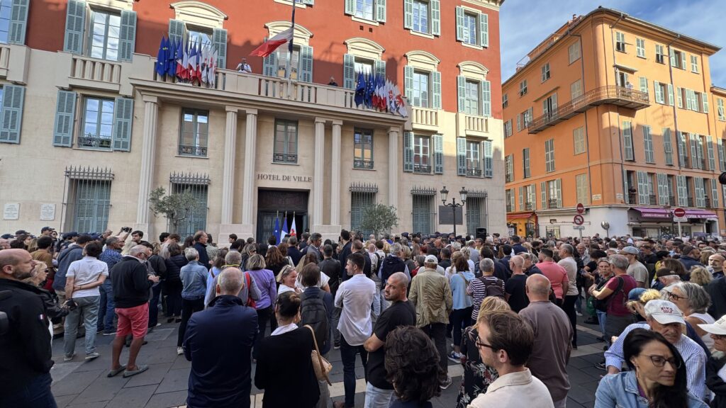 Foule rassemblée devant l'hôtel de ville de Nice, drapeaux français et européens au balcon